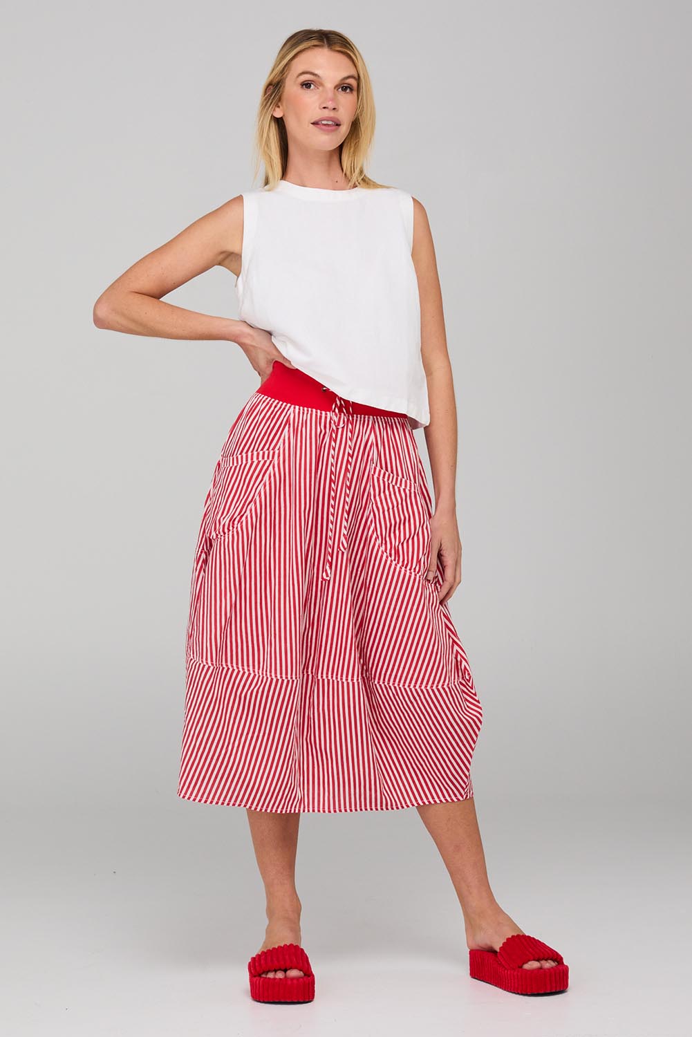 A model wearing the Guru Cotton Skirt in colour Emilias (Red), from the front, showing the whole outfit