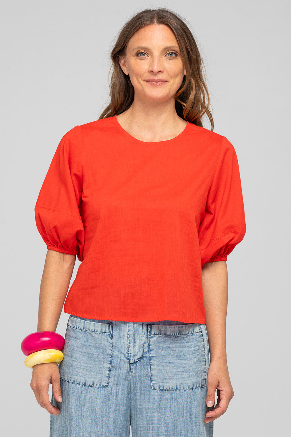 A model wearing the Ava Cotton Top in colour Pomodoro (Red), from the front, cropped image