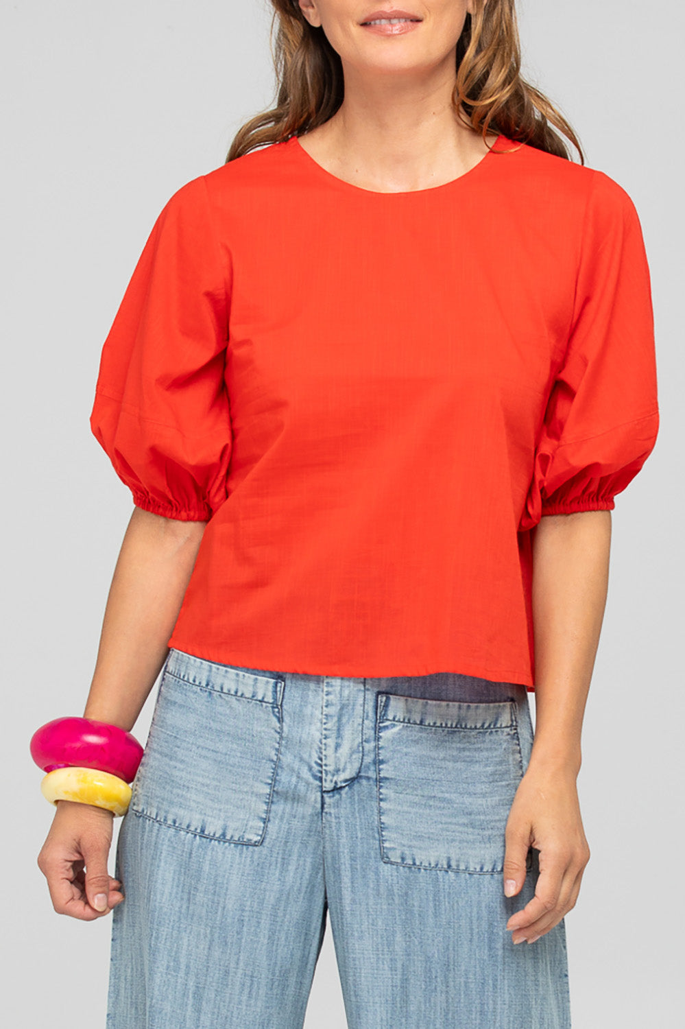 A model wearing the Ava Cotton Top in colour Pomodoro (Red), from the front, cropped image