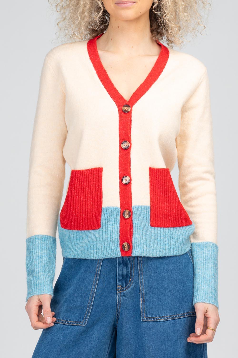 A model wearing the Poet Cardigan in colour Cream, from the front, cropped image