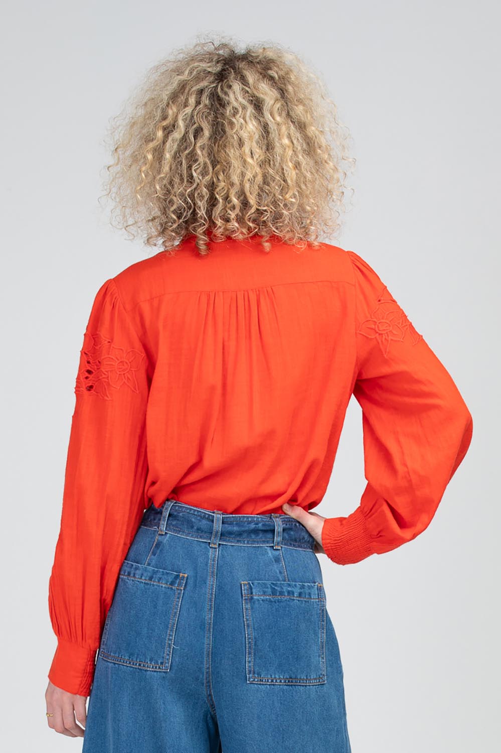 A model wearing the Clementine Cotton Shirt in colour Poppyred (Red), from the back