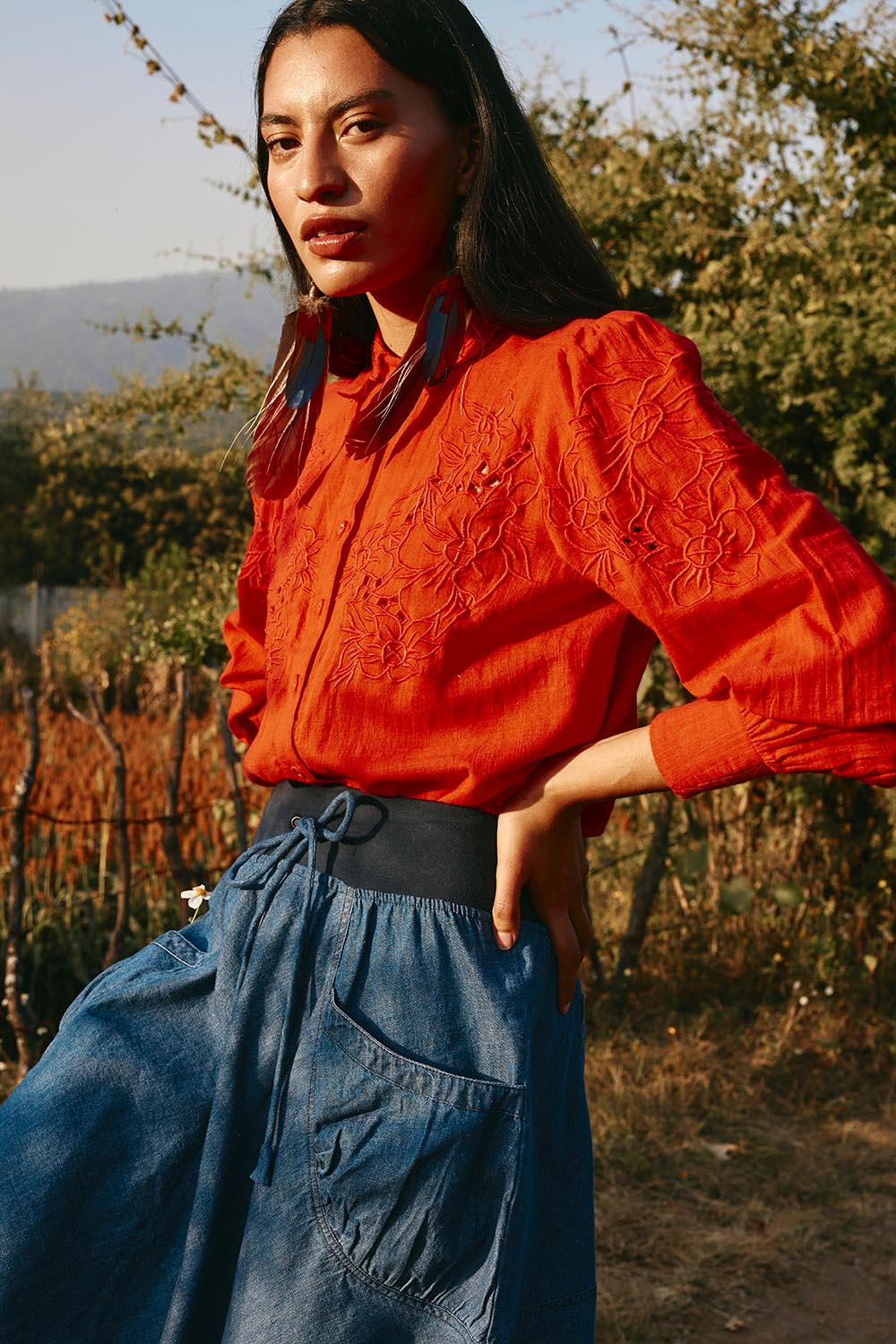A model wearing the Clementine Cotton Shirt in colour Poppyred (Red), from the front, showing the whole outfit