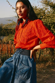 A model wearing the Clementine Cotton Shirt in colour Poppyred (Red), from the front, showing the whole outfit