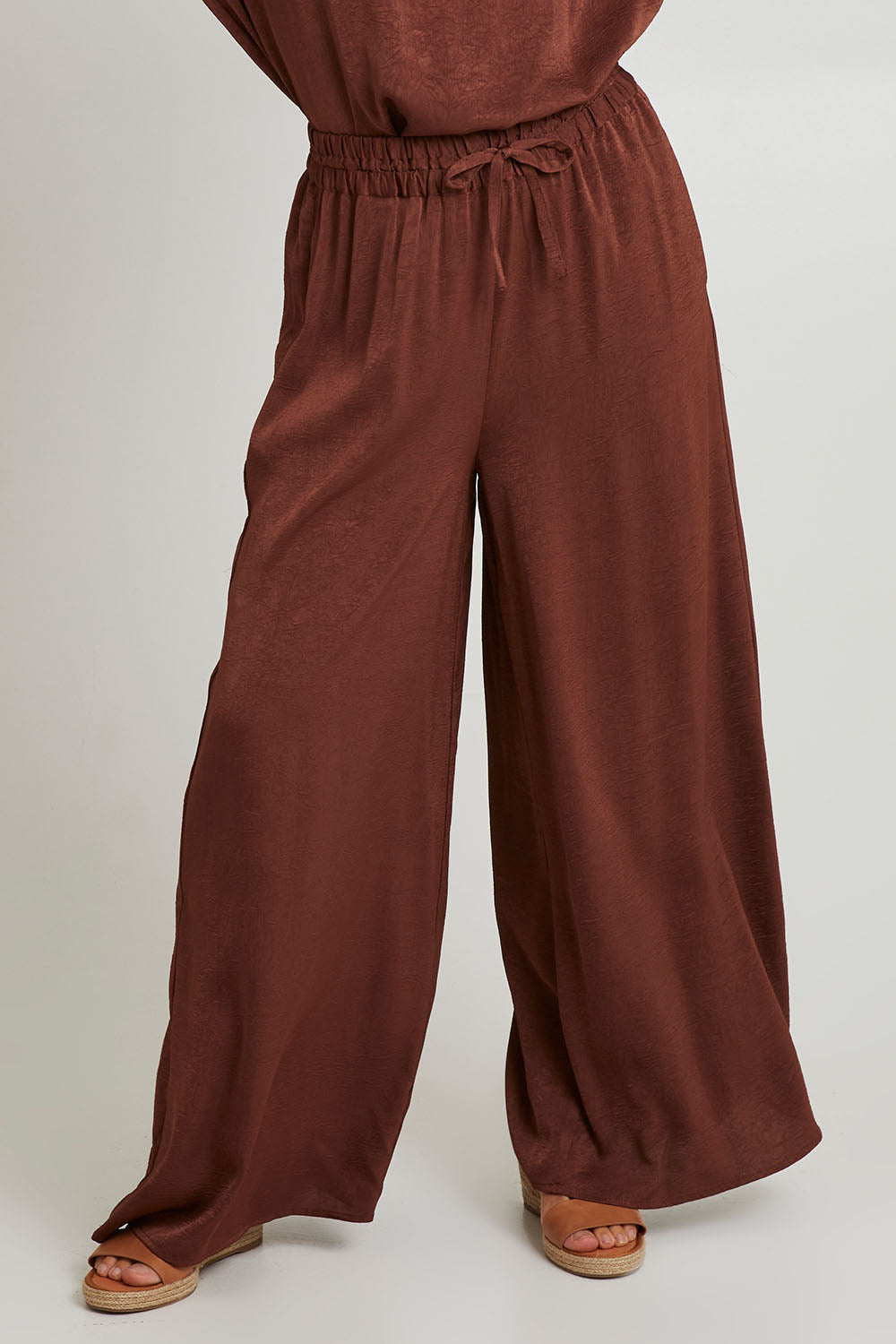 Model Katie wearing size S of the Liza Pant in colour Cocoa, from the front, cropped image