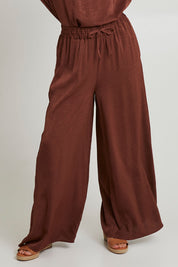 Model Katie wearing size S of the Liza Pant in colour Cocoa, from the front, cropped image