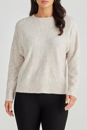 A model wearing the Saintly Knit in colour Parchment, from the front, cropped image