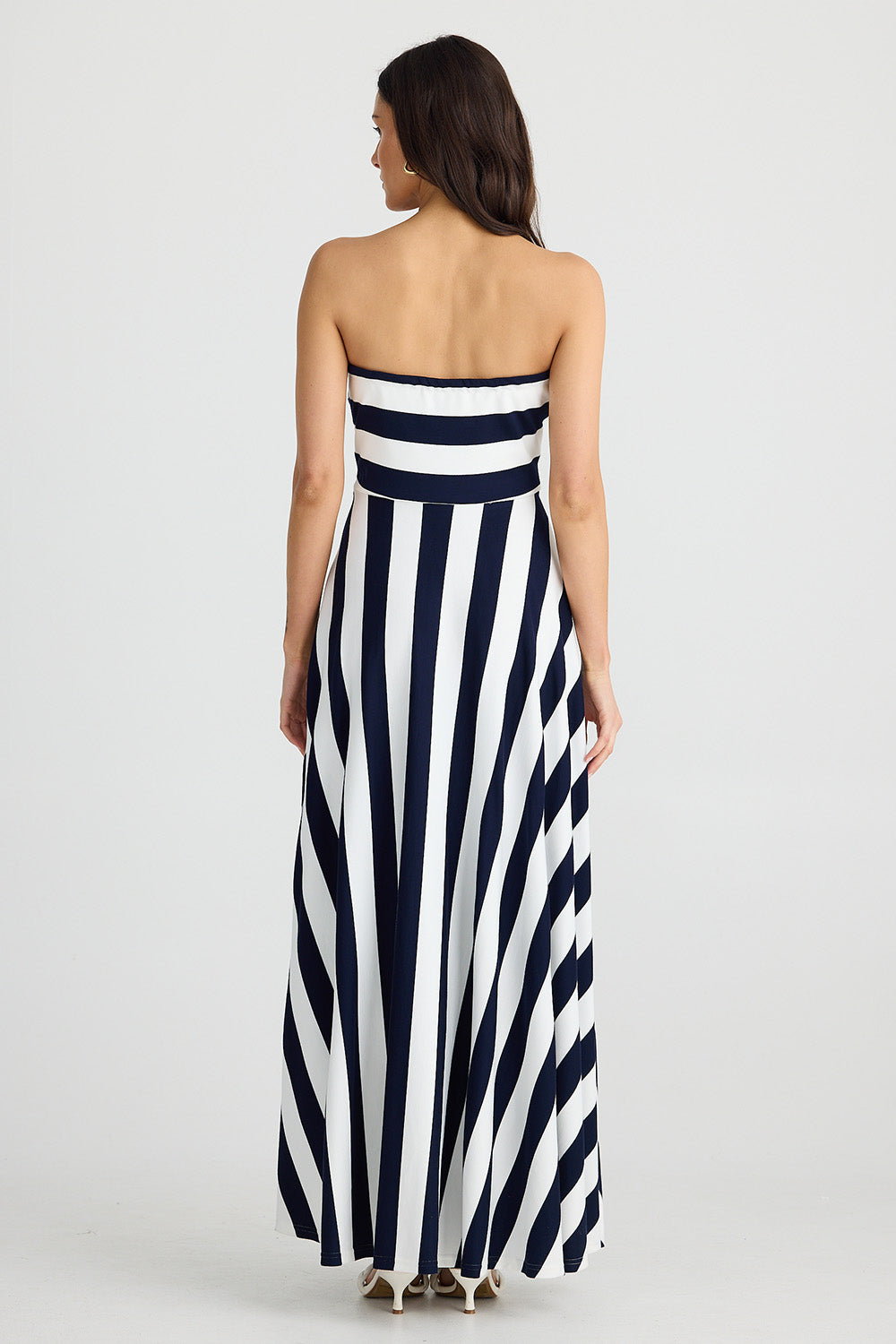 A model wearing the Thandie Strapless Dress in colour Navystripe (Blue), from the back