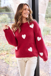 A model wearing the Heart On My Sleeve Knit in colour Cherrywhit (Red), from the front, showing the whole outfit
