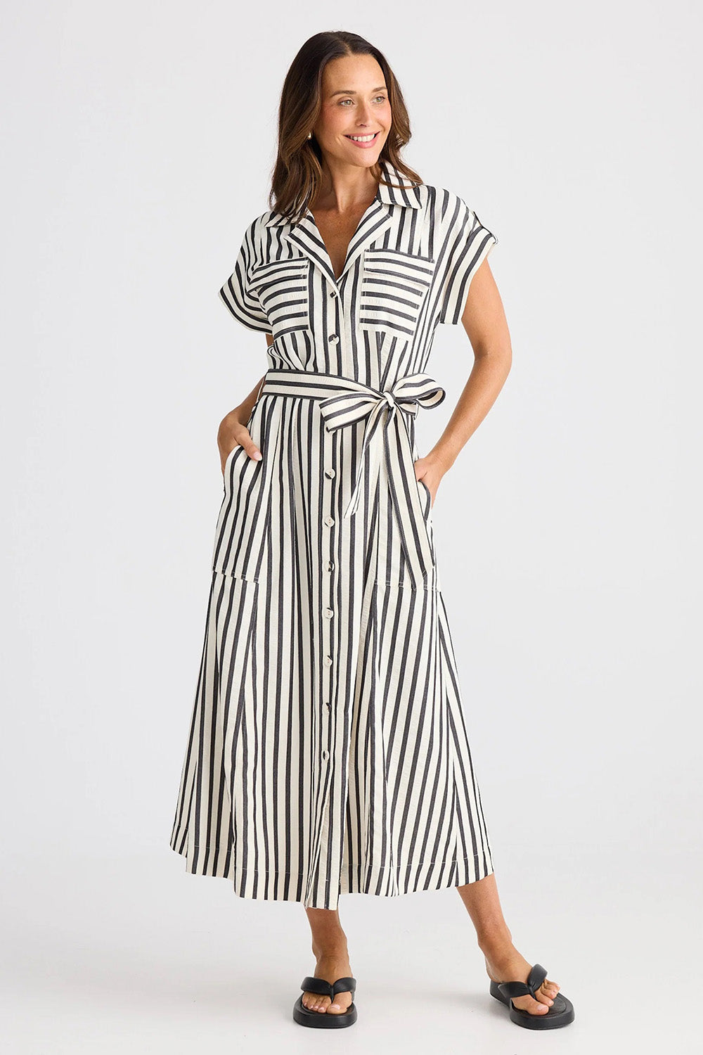 A model wearing the Portia Dress in colour Blackstrip, from the front, showing the whole outfit