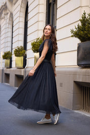 A model wearing the Carrie Skirt in colour Black (Black), from the front, showing the whole outfit