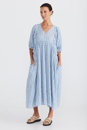 A model wearing the Ciao Bella Dress in colour Bluecheck (Blue), from the front, showing the whole outfit