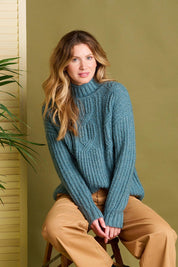 A model wearing the Cable Knitted Roll Neck Jumper in colour Blue (Blue), from the front, showing the whole outfit