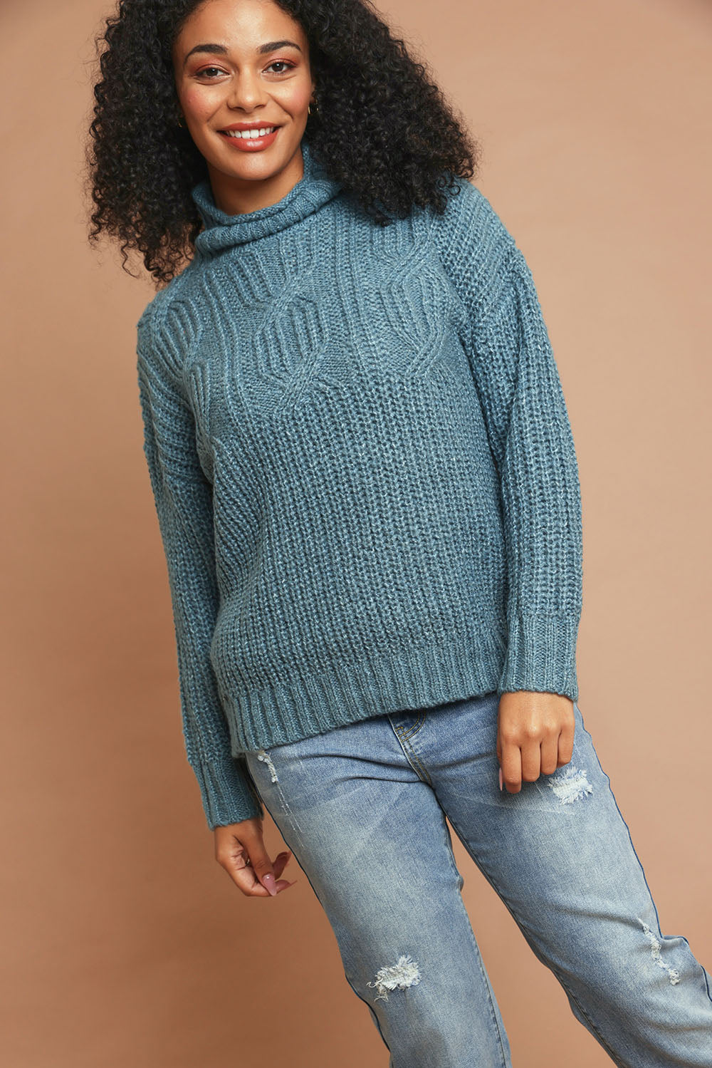 Model Ziara wearing size 10 of the Cable Knitted Roll Neck Jumper in colour Blue (Blue), from the front, showing the whole outfit