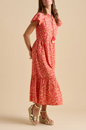 A model wearing the Sundown Cotton Maxi Dress in colour Coral, from the front, cropped image