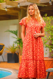 A model wearing the Sundown Cotton Maxi Dress in colour Coral, from the front, showing the whole outfit