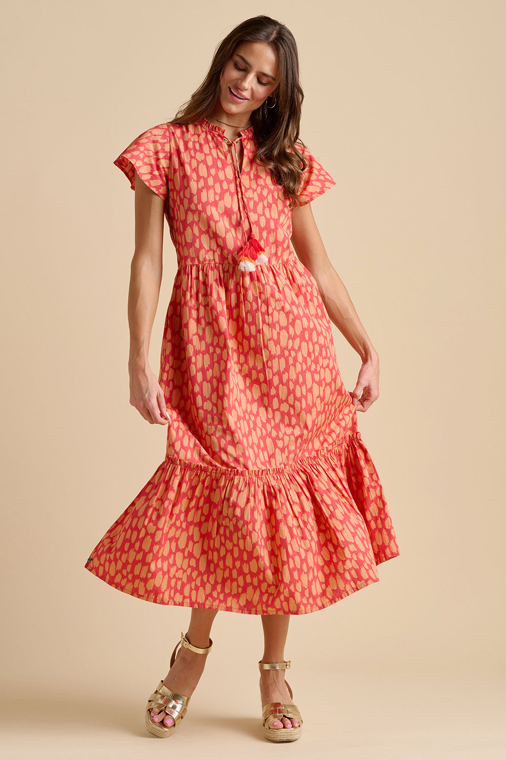 A model wearing the Sundown Cotton Maxi Dress in colour Coral, from the front, showing the whole outfit