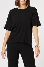 A model wearing the Lounge Top in colour Black (Black), from the front, cropped image