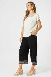 A model wearing the Cross Stitch Cotton Tee in colour Natural, from the front, showing the whole outfit