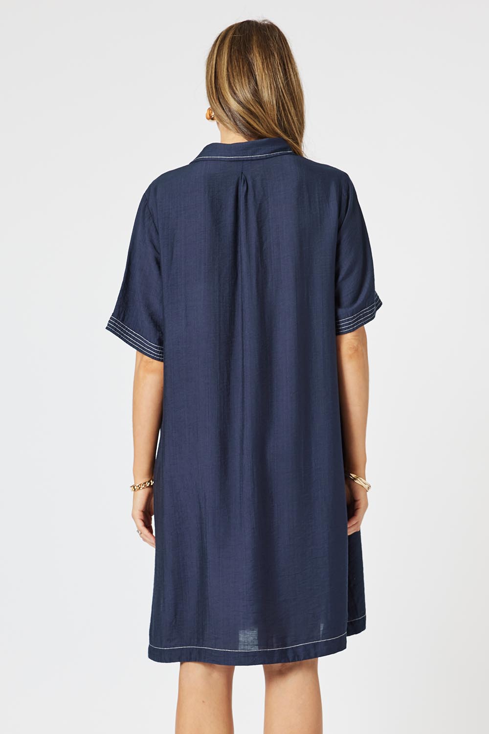 A model wearing the Top Stitch Dress in colour Navy (Blue), from the back