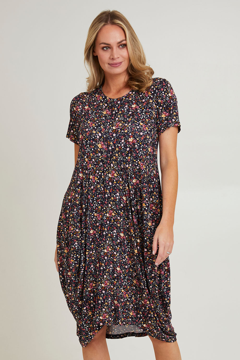Model Grace wearing size 10 of the Cap Sleeve Bounce Dress in colour Floral (Black), from the front, cropped image
