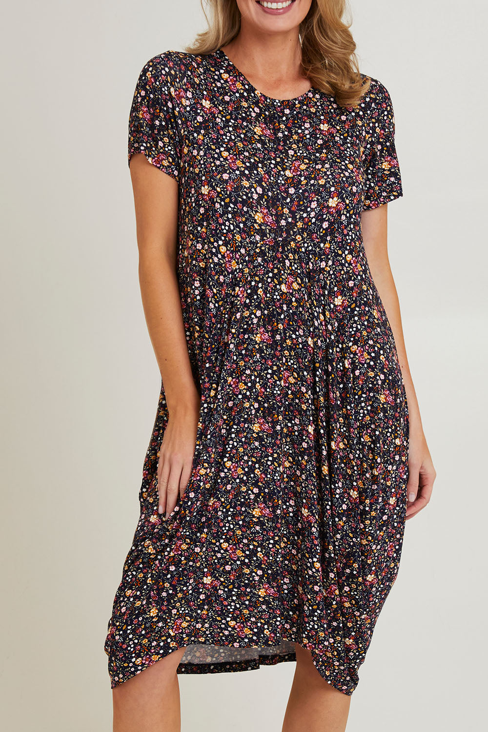 Model Grace wearing size 10 of the Cap Sleeve Bounce Dress in colour Floral (Black), from the front, cropped image