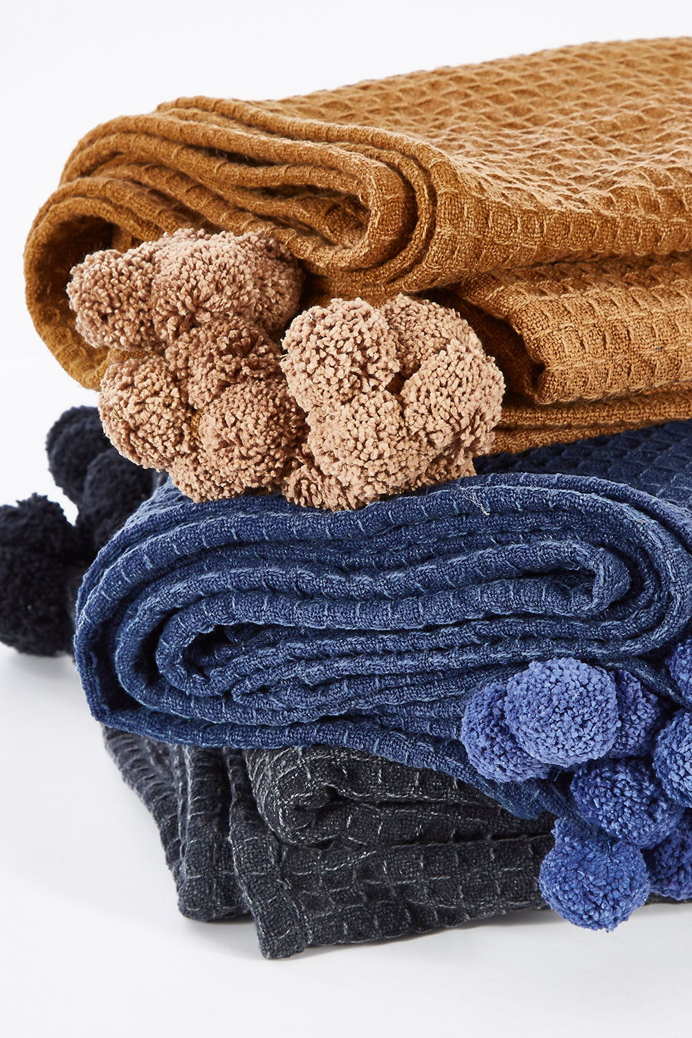 A model wearing size OneSize of the Textured Cotton Throw With Pompoms in colour Rust, from the front, showing the whole outfit