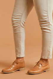 A model wearing size 39 of the Karaf Flat in colour Tan, from the front, cropped image