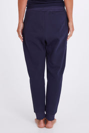 Model Alex wearing the Nova Pant in colour Navy (Blue), from the back