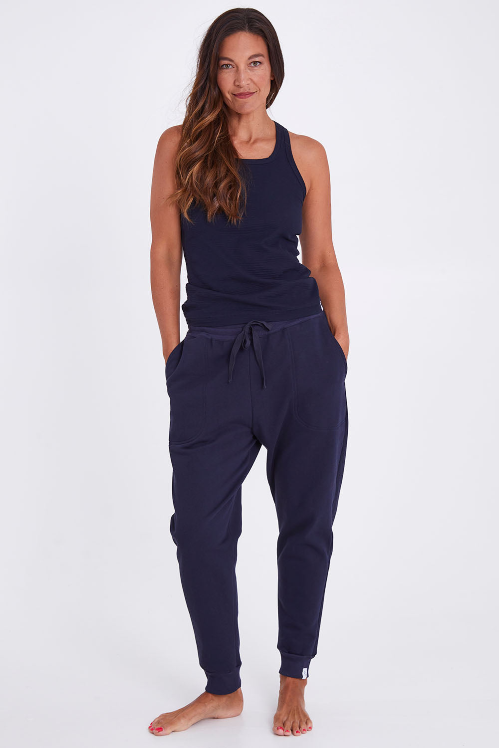 Model Alex wearing the Nova Pant in colour Navy (Blue), from the front, showing the whole outfit