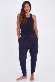 Model Alex wearing the Nova Pant in colour Navy (Blue), from the front, showing the whole outfit