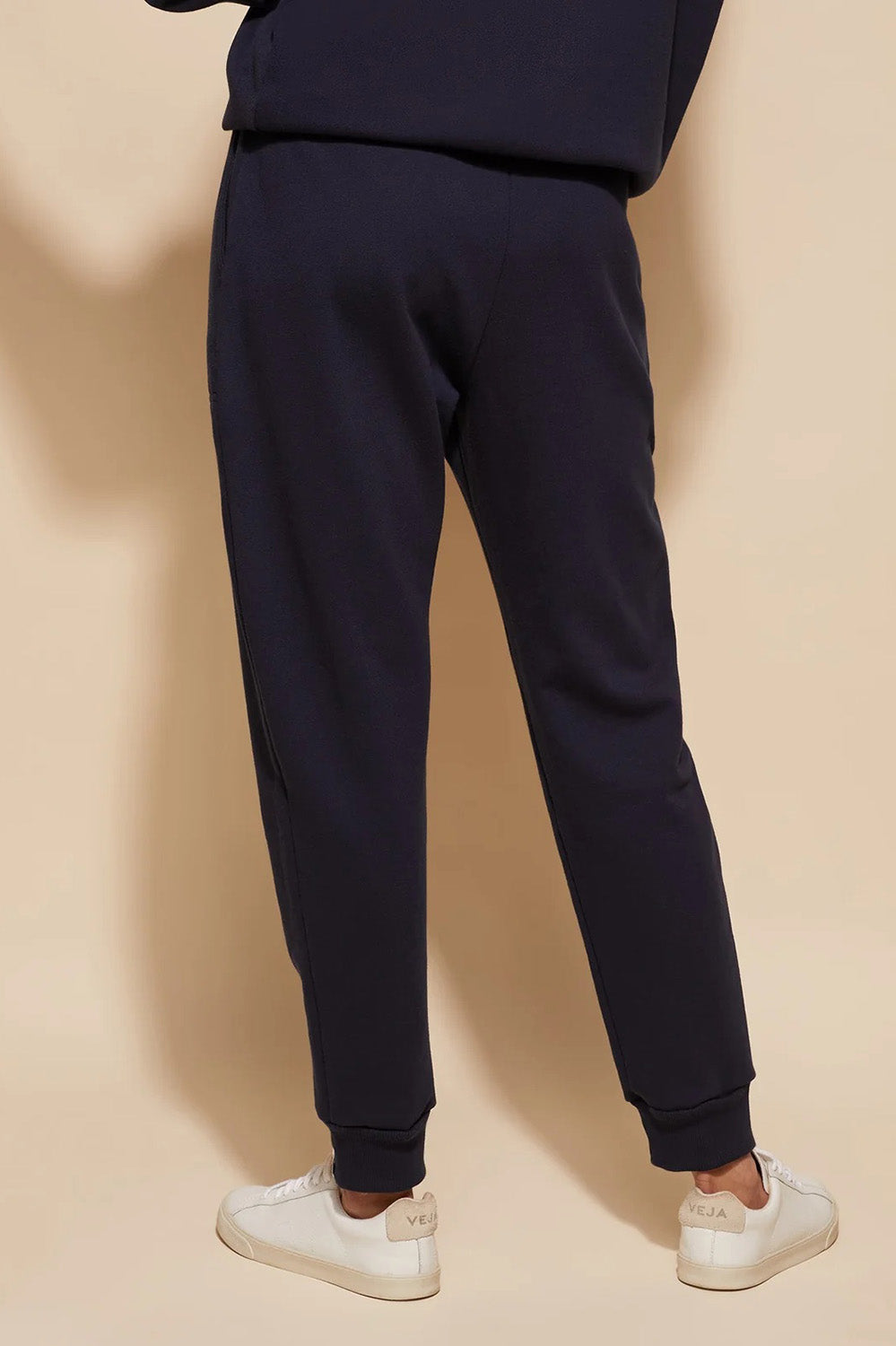 A model wearing the Nova Pant in colour Navy (Blue), from the back