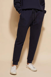 A model wearing the Nova Pant in colour Navy (Blue), from the front, cropped image