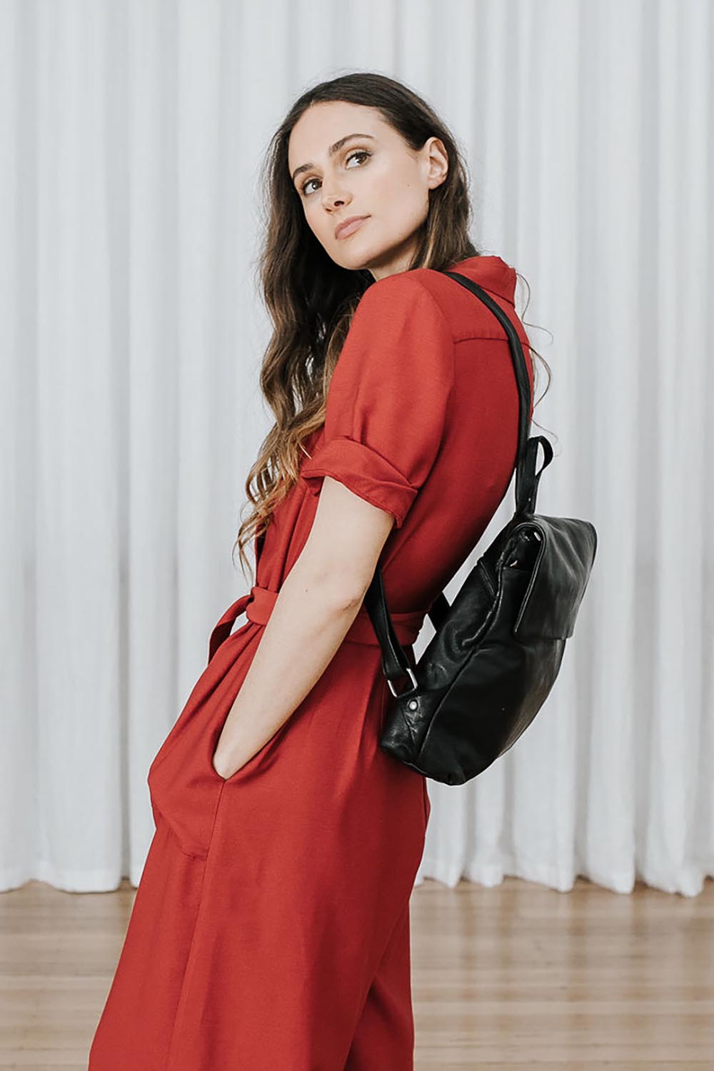 A model wearing the Neve Leather Backpack in colour Black (Black), from the front, showing the whole outfit