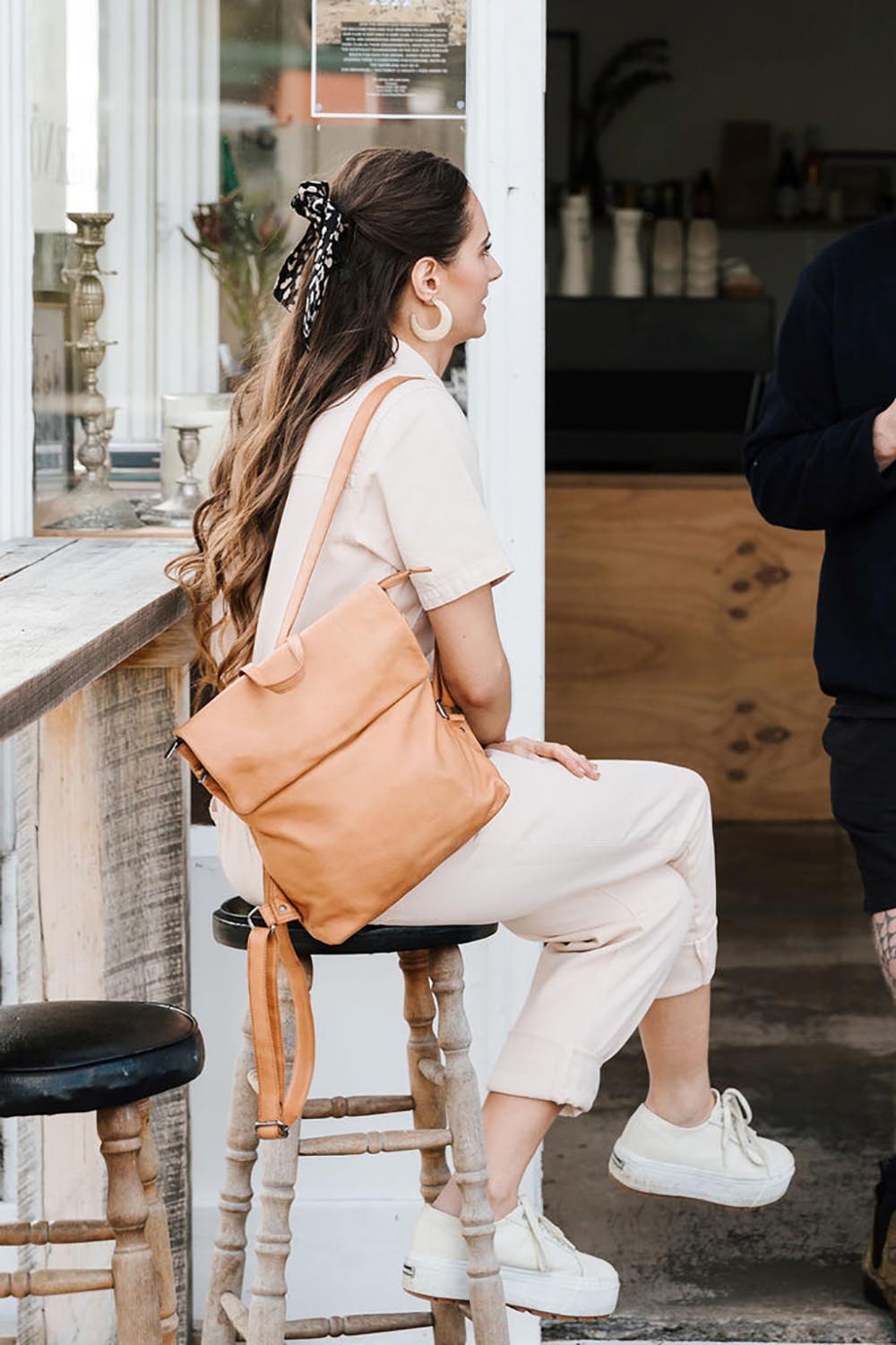 A model wearing the Neve Leather Backpack in colour Tan, from the front, showing the whole outfit