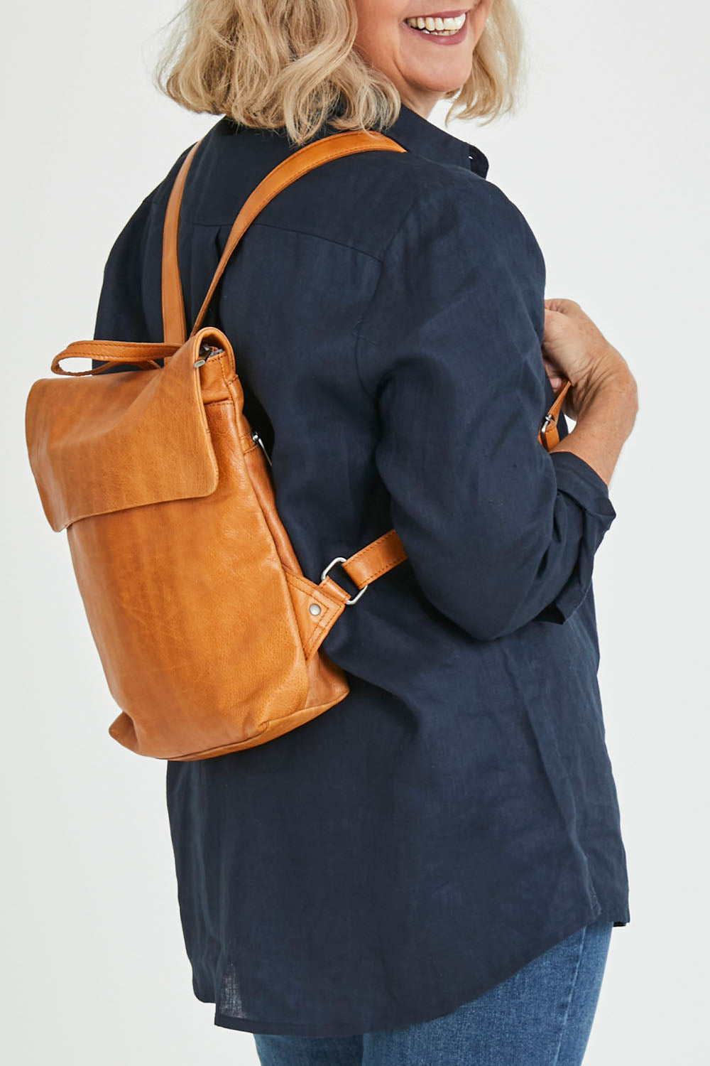 Model Sandy wearing size OneSize of the Neve Leather Backpack in colour Tan, from the front, cropped image