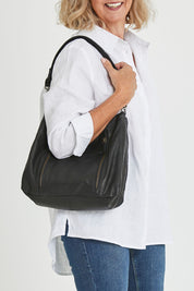 Model Sandy wearing size OneSize of the Poppy Leather Bag in colour Black (Black), from the front, cropped image