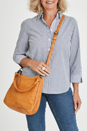 Model Sandy wearing size OneSize of the Poppy Leather Bag in colour Tan, from the front, cropped image