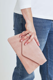 Model Steph wearing the Riley Leather Clutch in colour Duskypink (Pink), from the front, cropped image