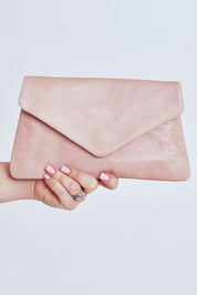 Model Steph wearing the Riley Leather Clutch in colour Duskypink (Pink), from the front, cropped image