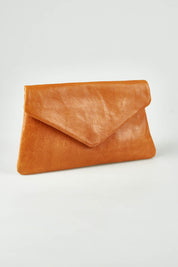 A model wearing the Riley Leather Clutch in colour Tan, from the front, showing the whole outfit