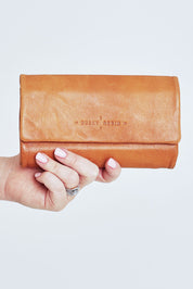 Model Steph wearing size OneSize of the Rose Leather Purse in colour Tan, from the front, cropped image