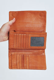 Model Steph wearing size OneSize of the Rose Leather Purse in colour Tan, from the front, cropped image