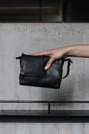 A model wearing the Sara Leather Bag in colour Black (Black), from the front, showing the whole outfit