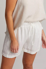 A model wearing the Studio Linen Short in colour Salt (White), from the front, cropped image