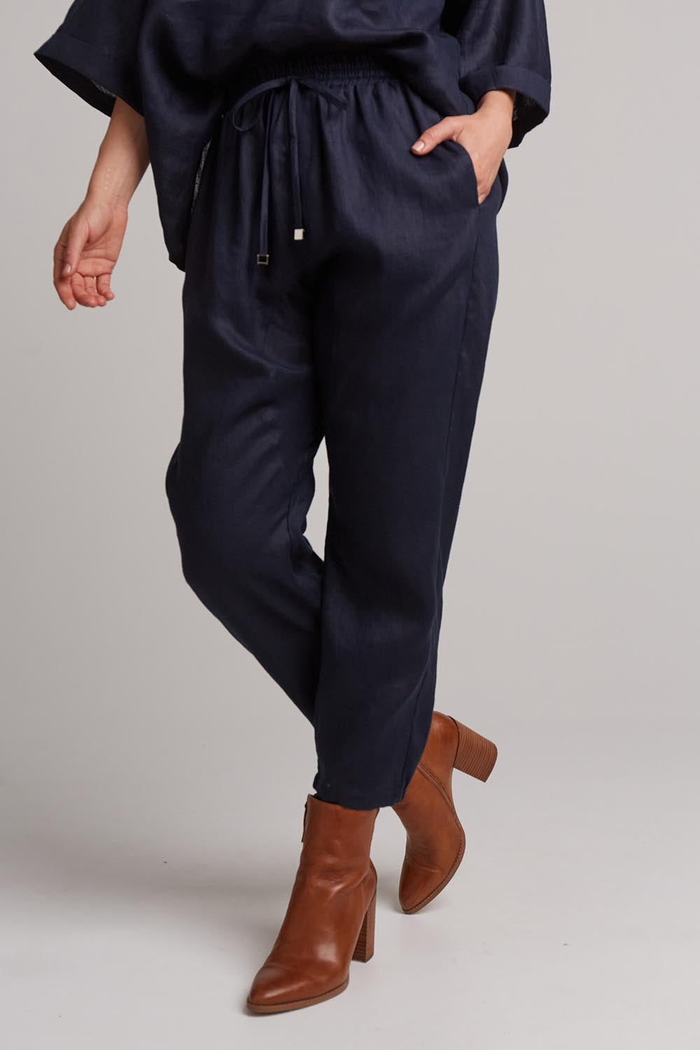 A model wearing the Studio Relaxed Linen Pant in colour Navy (Blue), from the front, cropped image