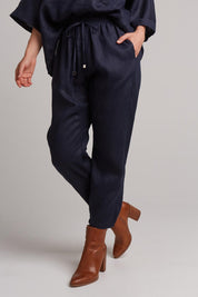 A model wearing the Studio Relaxed Linen Pant in colour Navy (Blue), from the front, cropped image
