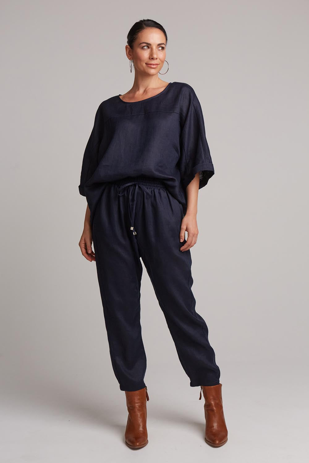 A model wearing the Studio Relaxed Linen Pant in colour Navy (Blue), from the front, showing the whole outfit