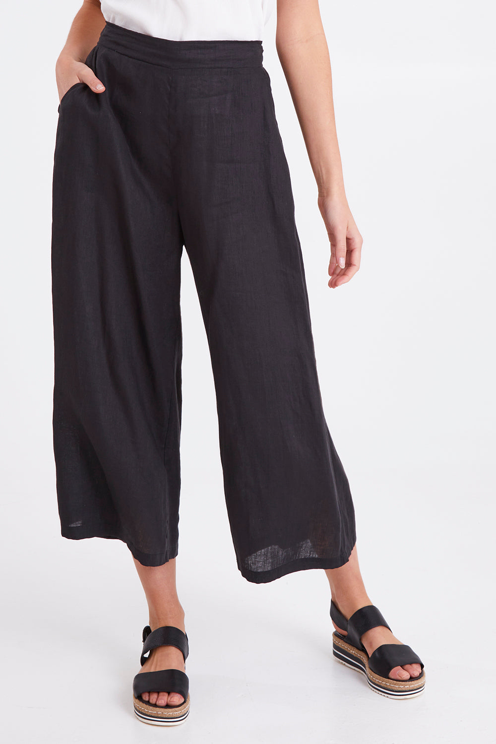 Model Madeline wearing size S of the Studio Crop Pant in colour Ebony (Black), from the front, cropped image