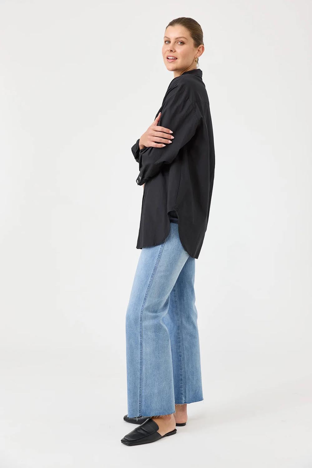 A model wearing the Studio Oversize Cotton Shirt in colour Ebony (Black), from the front, showing the whole outfit