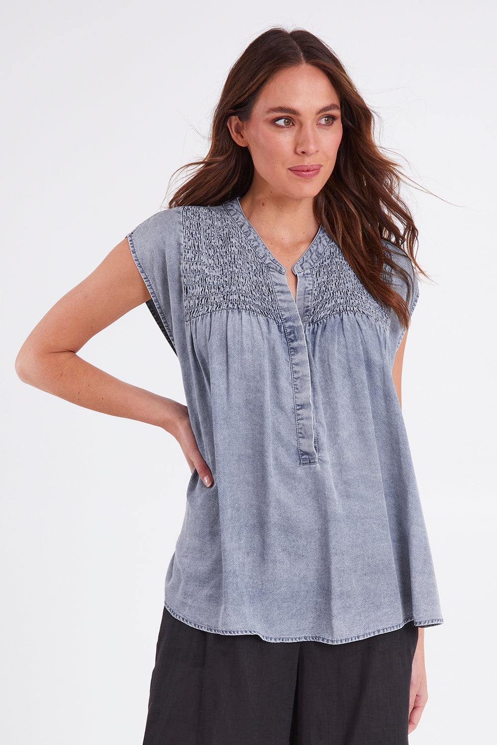 Model Madeline wearing size S of the Elan Top in colour Denim (Blue), from the front, cropped image